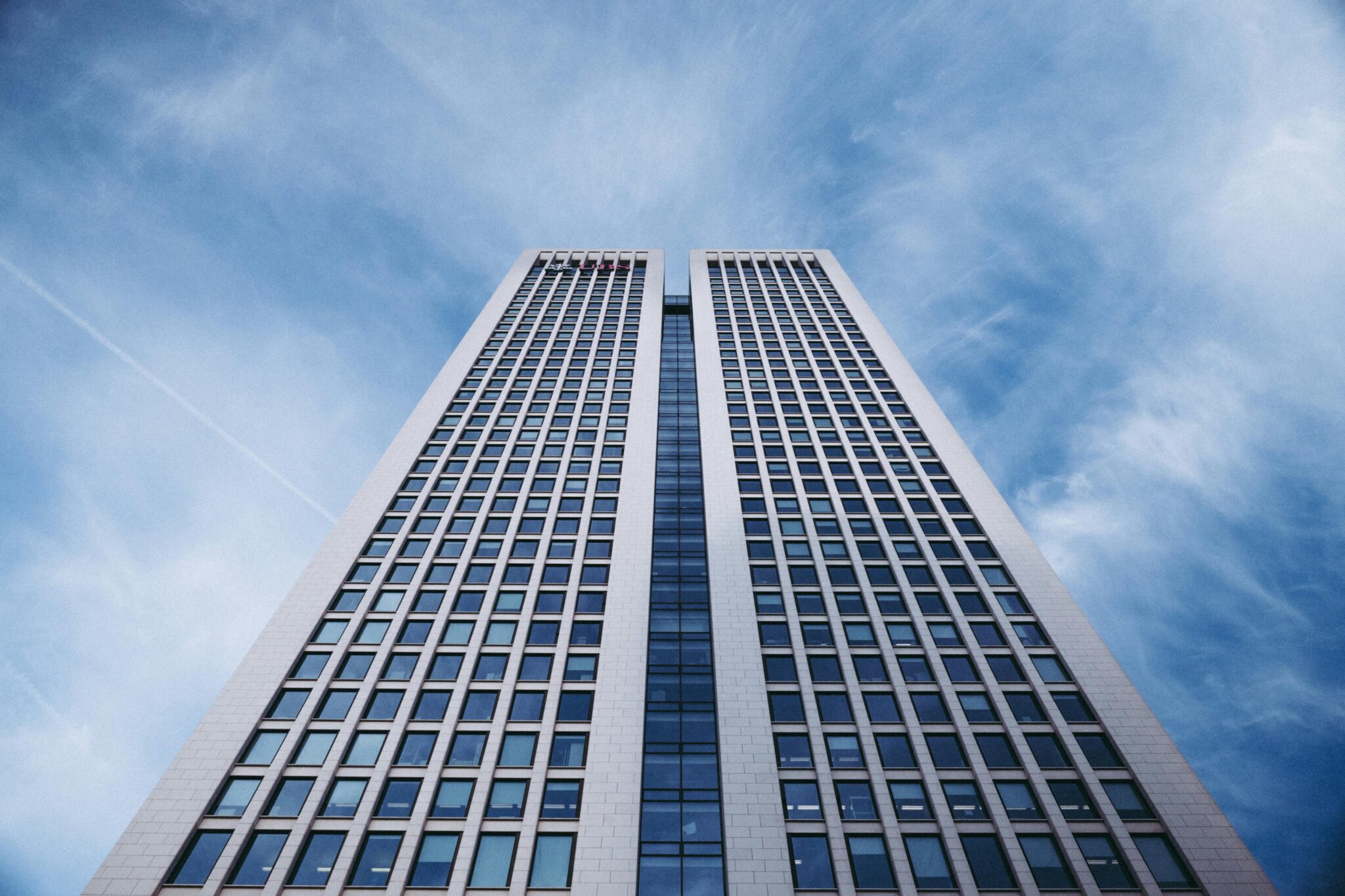 Low-angle view of a modern skyscraper with a stunning blue sky backdrop.